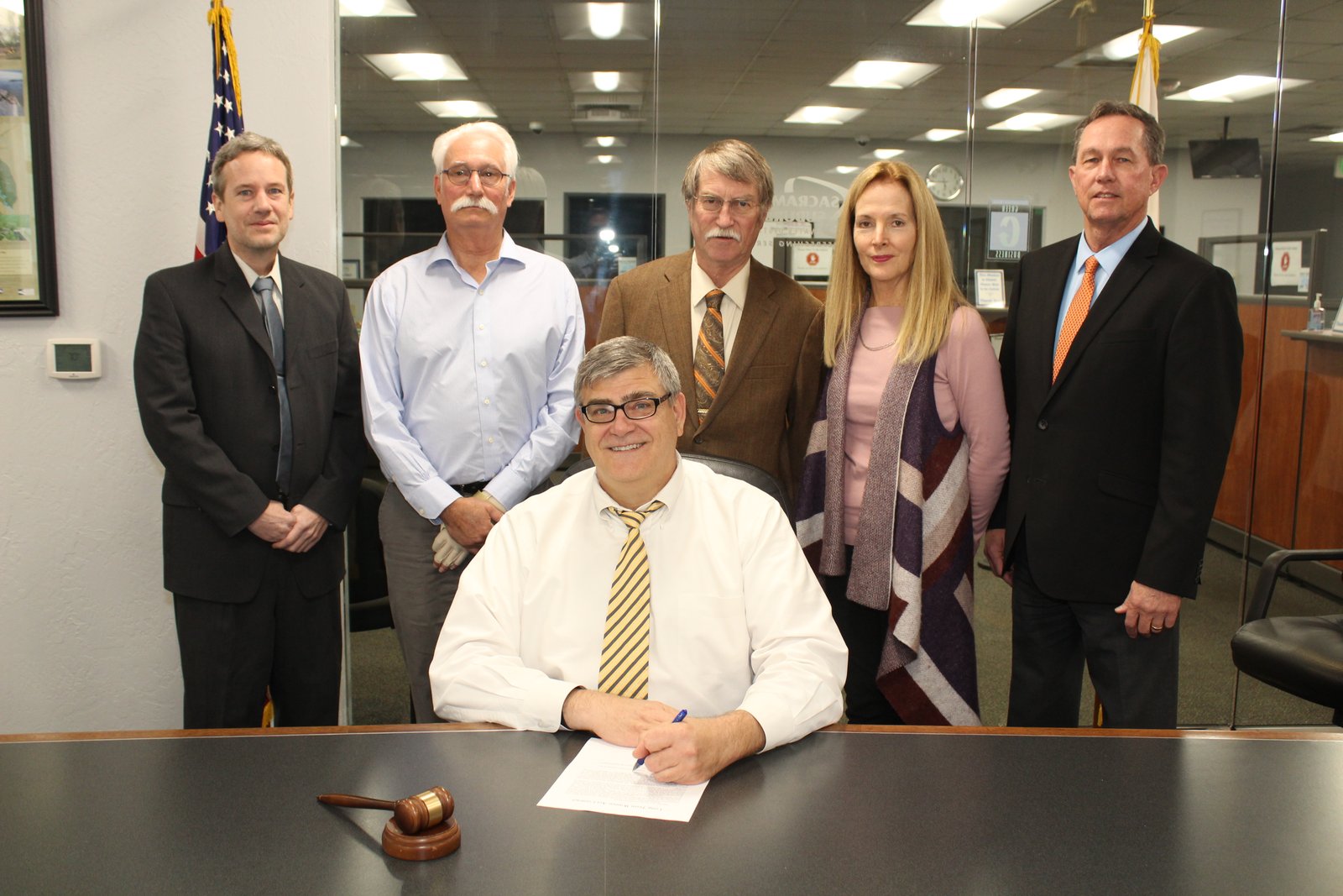 Craig Locke, seated, signs the long-term Warren Act contract as SSWD colleagues stand behind him.